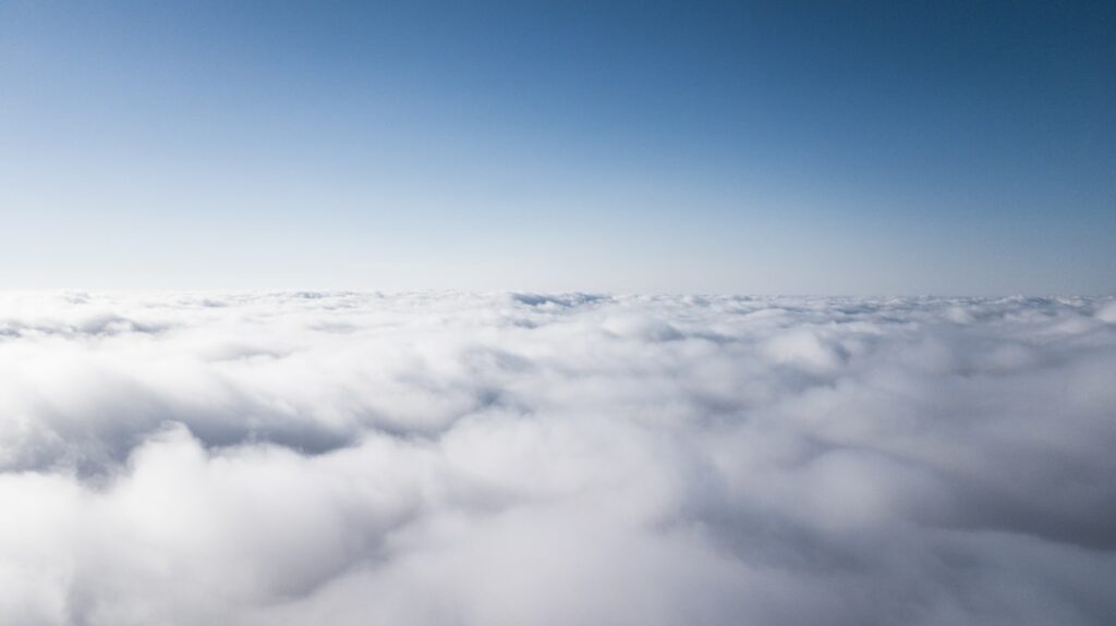 Picture taken above the clouds with a clear blue sky.