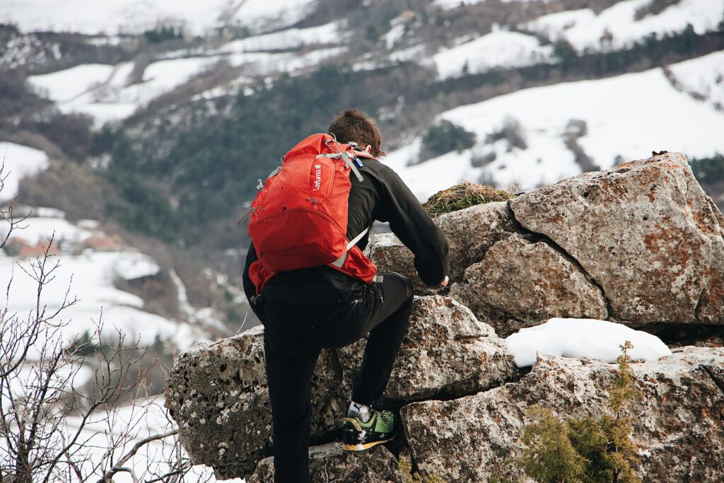 Man climbing a stone within a snow environment.