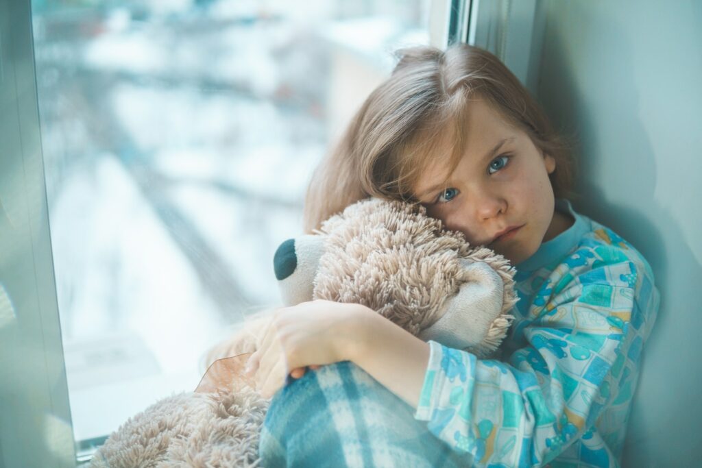 Child looking sad and under the weather with a teddy bear